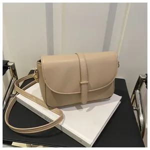Close-up of beige vegetable tanned leather handbag with minimalist gold buckle and flap