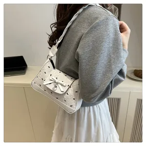 Détail du sac bandoulière blanc en PU avec imprimé nœud et pendentif cœur