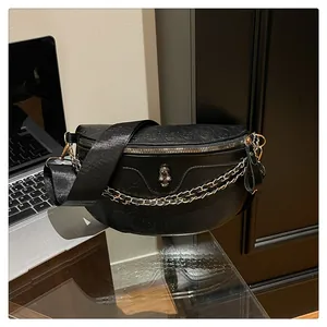 Detail of gothic black leather chest bag featuring skull embossing and silver chain strap