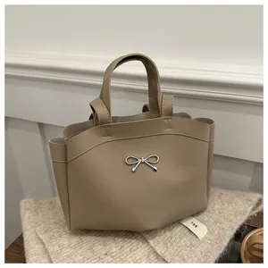 Close-up of khaki leather handbag with elegant silver metal bow buckle detail