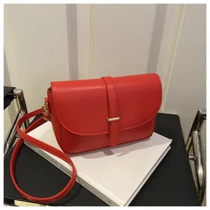 Detail of red genuine leather shoulder bag featuring a sleek gold metal bar on the flap