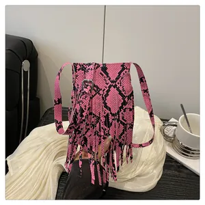 Detailed view of fuchsia faux leather crossbody bag featuring snakeskin texture and long tassels