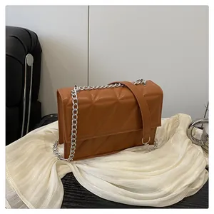 Detail of a brown quilted leather crossbody bag with elegant silver chain shoulder strap