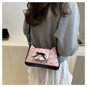 Détail du sac sous l'aisselle à nœud rose avec pendentif coeur et tissu plissé
