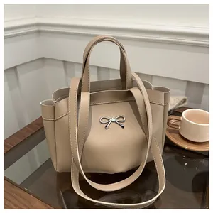 Detailed view of silver bow-knot metal buckle on a beige tote bag with smooth texture
