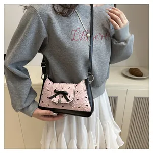 Détail du sac croissant rose avec petits nœuds noirs et pendentif en forme de cœur