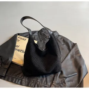 Detail of black suede hobo bag with studded texture and leather strap on modern background