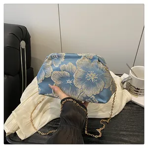 Detailed embroidery on light blue satin cloud bag with elegant gold chain handle