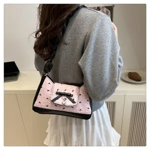 Détail du sac croissant plissé rose avec des nœuds noirs et un pendentif coeur