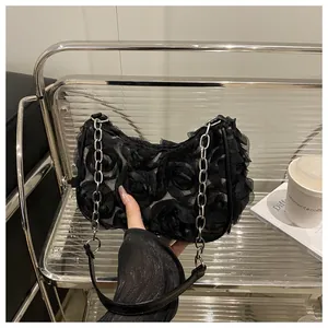 Détail du sac d'épaule en maille noire avec pétales de rose 3D et bandoulière chaîne