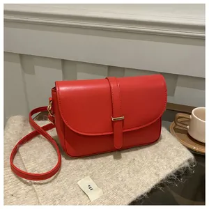 Close-up of red vegetable tanned leather handbag with gold buckle on a knitted background