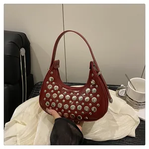 Detail of dark red patent leather underarm bag featuring silver punk style rivets and moon shape