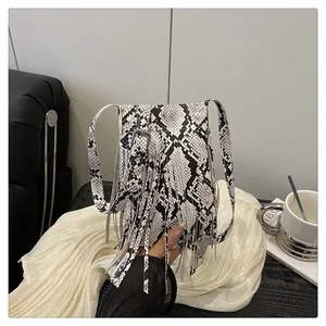 Detail of snake skin texture and long fringe tassels on a crossbody messenger bag