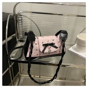 Détail du sac à main rose avec nœud noir papillon et pendentif en forme de cœur