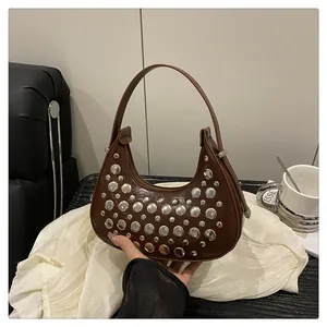 Detail of dark brown faux leather underarm bag with silver studs and wide handle