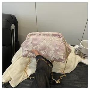 Detail of pink satin makeup bag with white 3D floral embroidery and gold chain