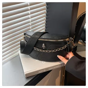 Close-up of gothic black leather chest bag with skull embossing and metal chain detail