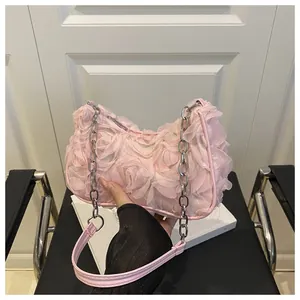 Détail de pétales de rose en tissu 3D et chaîne argentée sur sac de soirée rose