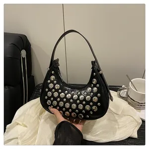 Close-up of black leather crescent bag featuring silver rivet stud accents and zipper