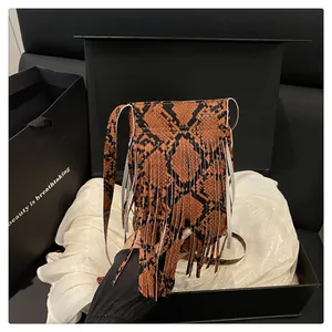 Detailed view of brown snakeskin texture crossbody bag with fringe in a luxury gift box