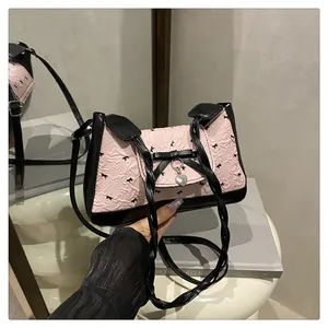 Détail du sac à bandoulière rose plissé avec imprimé nœud noir et pendentif cœur