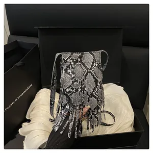 Macro detail of snakeskin pattern crossbody bag with long tassels in a premium gift box