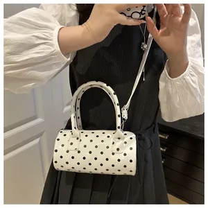 Mirror selfie showing the white polka dot cylinder handbag with top handles and strap
