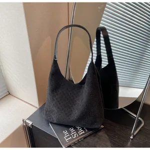 Detail of black suede hobo bag featuring sparkling rhinestones and a leather shoulder strap