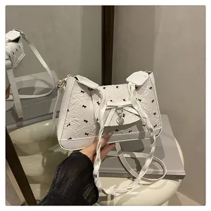 Détail du sac blanc avec texture florale, imprimé nœud noir et pendentif cœur argenté