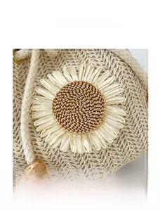 Close-up of woven straw bucket bag with large 3D floral decoration and metal toggle detail