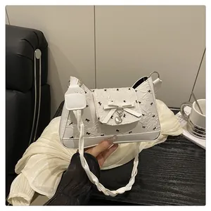 Gros plan du sac à bandoulière blanc plissé avec nœuds noirs et pendentif en cœur
