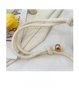 Close-up of woven rope handle with gold metal beads on the straw bucket bag