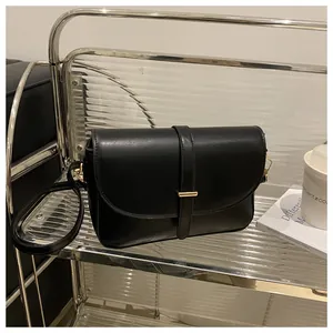Detailed shot of black minimalist leather handbag featuring a sleek gold metal buckle