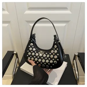 Detail of black crescent handbag featuring silver metal rivets and polished leather finish