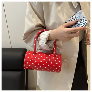 Close-up of red polka dot cylinder bag featuring glossy finish and smooth zipper detail