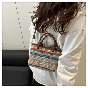 Detail of colorful striped woven tote bag with brown leather handles and gold metal rings