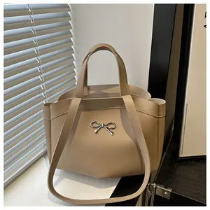 Detail view of khaki tote bag with silver bow ornament and smooth PU leather texture
