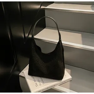 Close-up of black suede hobo bag with sparkling rhinestones placed on design books
