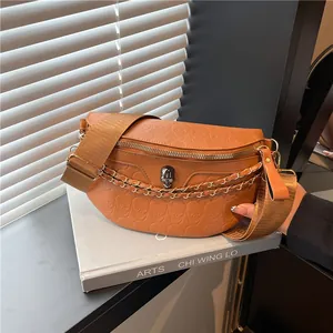Brown moon-shaped chest bag with skull embossing and chain detail on art book