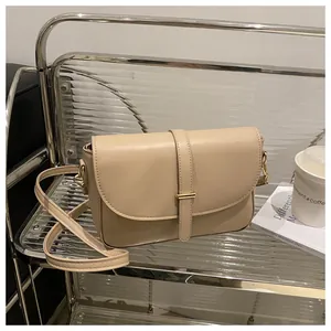 Close-up of beige leather crossbody bag with elegant gold hardware and textured finish