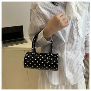 Detail shot of a black and white polka dot cylindrical handbag with gloss finish
