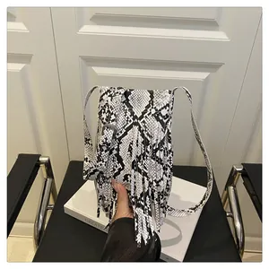 Detail shot of the faux snakeskin texture and long fringes on this chic crossbody bag