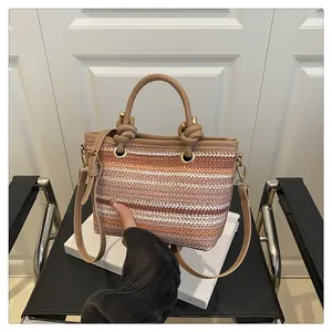 Close-up of woven striped handbag with knotted handles and gold-tone metal hardware