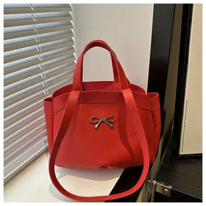 Detail of red PU leather tote bag with silver bow ornament and fine matte texture