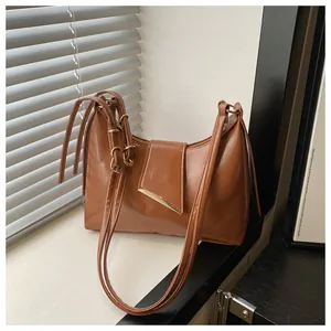Detail of vintage brown leather shoulder bag with glossy finish and gold metal buckle
