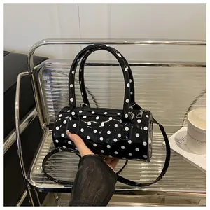 Close-up of a mini polka dot cylinder handbag with glossy finish and dual handles