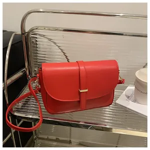 Detail of red vegetable tanned leather handbag with gold metal clasp and sleek texture