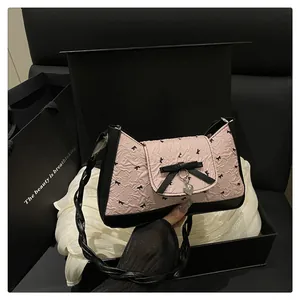 Détail du sac rose avec nœud, pendentif cœur et bandoulière tressée en coffret
