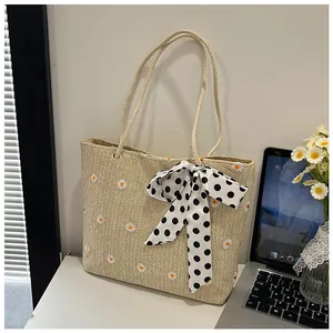 Detail of straw tote bag with daisy embroidery and black polka dot bow accent