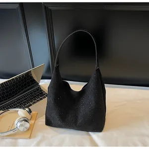 Close-up of a black rhinestone hobo bag on a desk with lifestyle office accessories